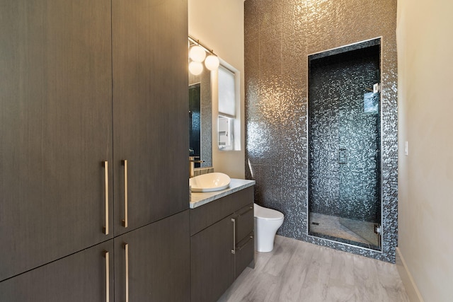 bathroom featuring a shower with door, vanity, hardwood / wood-style flooring, and toilet