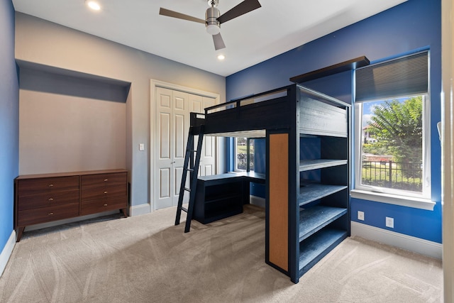 unfurnished bedroom featuring light carpet, a closet, and ceiling fan