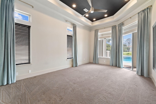 unfurnished room with ceiling fan, light colored carpet, ornamental molding, and a raised ceiling