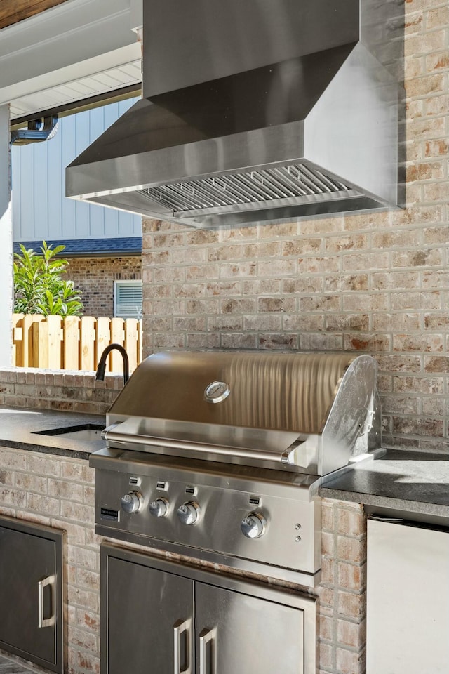 kitchen featuring wall chimney exhaust hood and brick wall