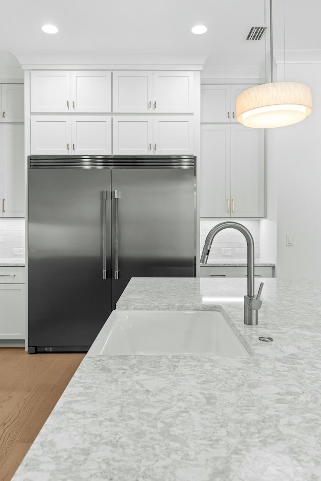 kitchen with stainless steel built in fridge, white cabinetry, and tasteful backsplash