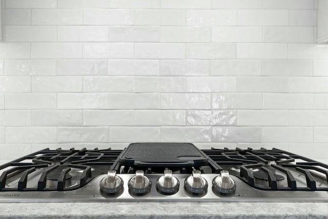 room details featuring backsplash, light stone countertops, and stainless steel gas stovetop