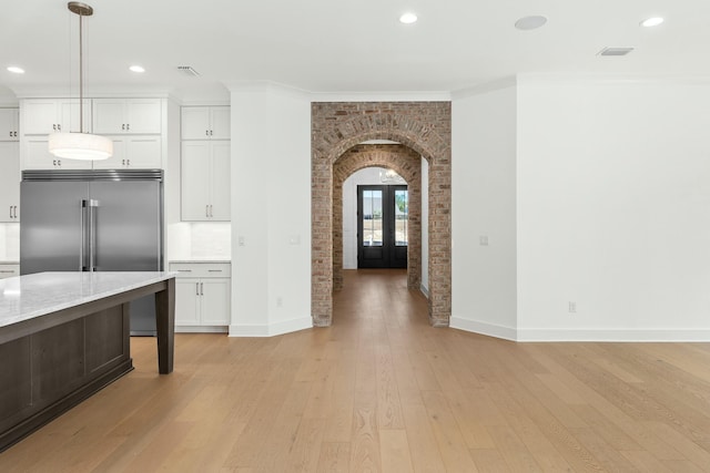 kitchen featuring decorative light fixtures, stainless steel built in refrigerator, white cabinetry, and backsplash