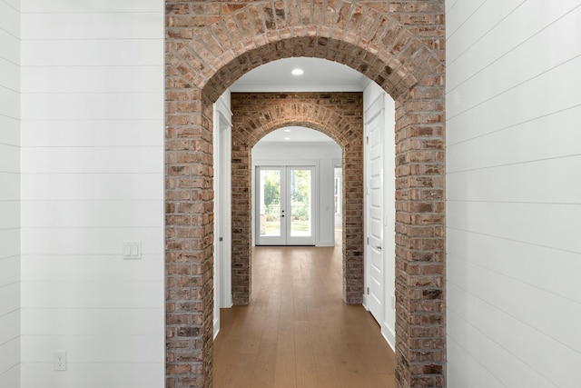 hallway with dark hardwood / wood-style floors, brick wall, and french doors