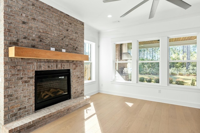 unfurnished living room featuring a fireplace, light hardwood / wood-style floors, and a wealth of natural light