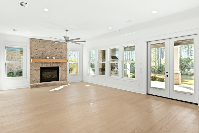 unfurnished living room featuring a fireplace, ceiling fan, french doors, and light wood-type flooring