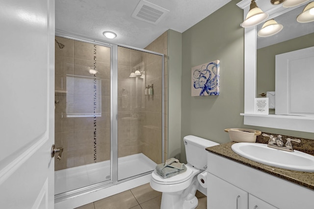 bathroom featuring a shower with door, tile patterned flooring, vanity, a textured ceiling, and toilet