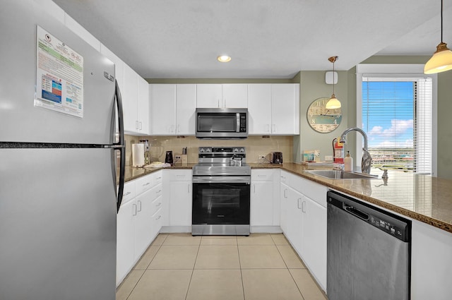 kitchen featuring appliances with stainless steel finishes, pendant lighting, sink, white cabinets, and decorative backsplash