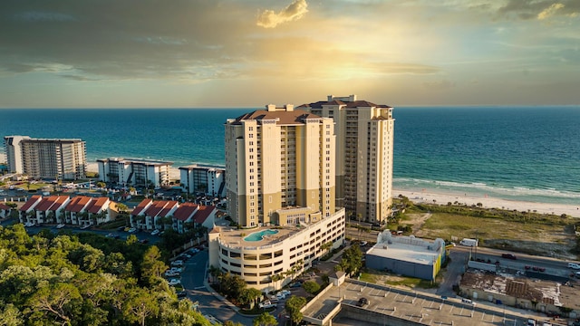 aerial view at dusk with a water view and a view of the beach