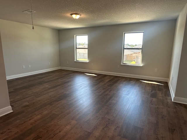 empty room with dark hardwood / wood-style floors, a textured ceiling, and a wealth of natural light