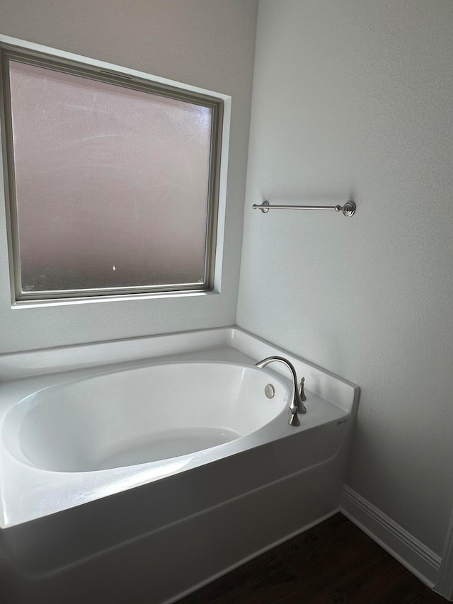 bathroom with a tub and hardwood / wood-style flooring