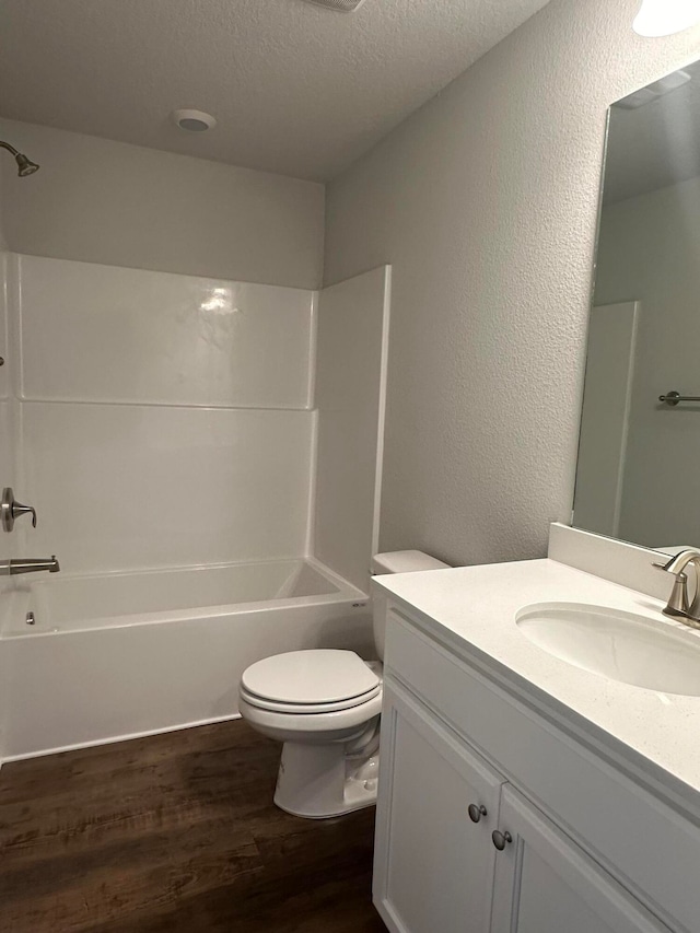 full bathroom featuring shower / bath combination, vanity, a textured ceiling, hardwood / wood-style floors, and toilet