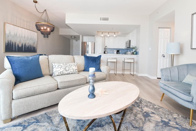 living room featuring light hardwood / wood-style flooring, rail lighting, a chandelier, and sink