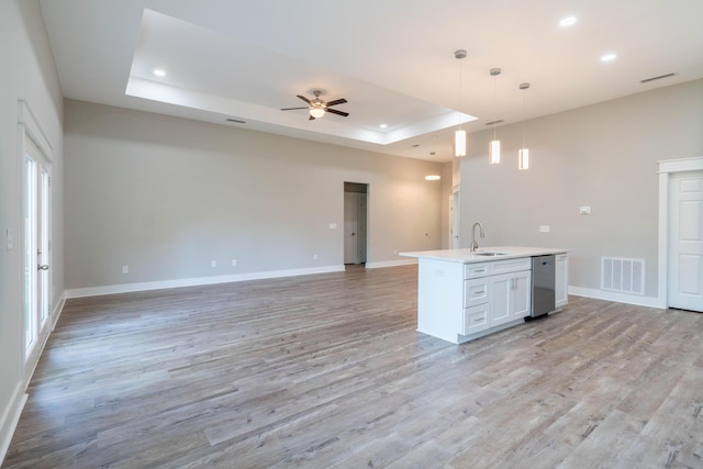 kitchen with pendant lighting, sink, light wood-type flooring, a tray ceiling, and white cabinetry