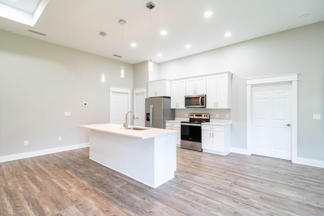 kitchen with a high ceiling, white cabinets, sink, hanging light fixtures, and appliances with stainless steel finishes