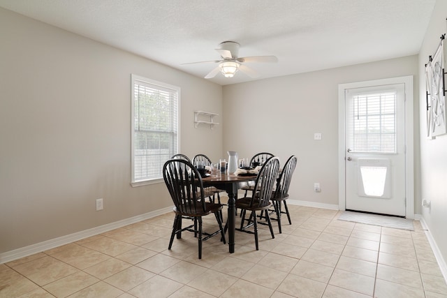 tiled dining area with ceiling fan, a healthy amount of sunlight, and a textured ceiling