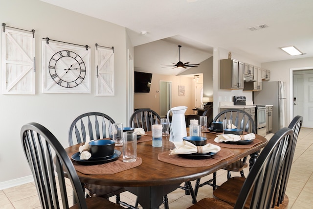 dining room featuring light tile patterned floors, a barn door, and ceiling fan