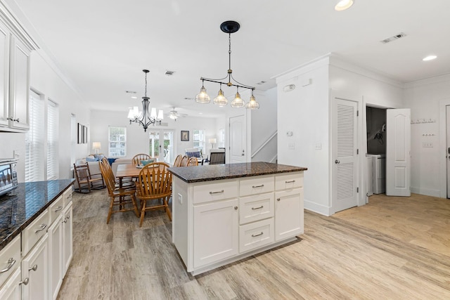 kitchen with light wood-type flooring, ceiling fan, pendant lighting, a kitchen island, and white cabinetry