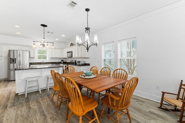 dining space featuring hardwood / wood-style flooring, ornamental molding, and a healthy amount of sunlight