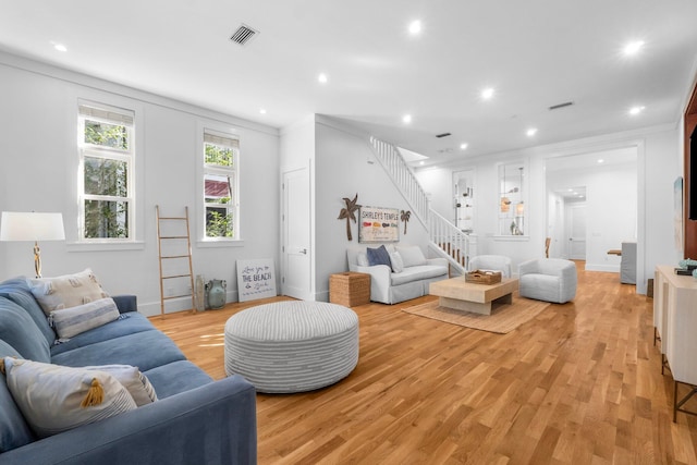 living room with ornamental molding and light hardwood / wood-style flooring