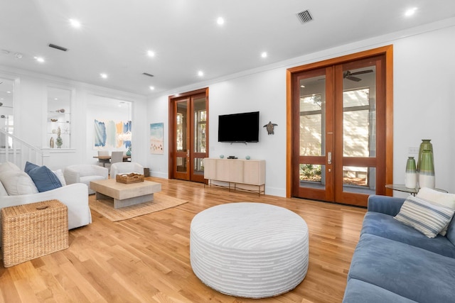 living room with light hardwood / wood-style floors, french doors, and ornamental molding