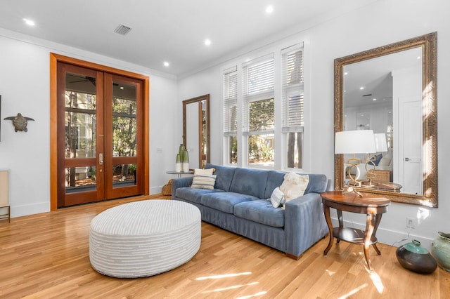 living area featuring light hardwood / wood-style floors, french doors, and crown molding