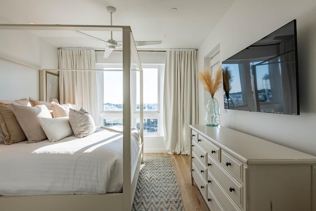 bedroom with ceiling fan, multiple windows, and light wood-type flooring