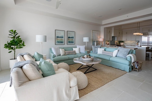 living room with a raised ceiling and light tile floors