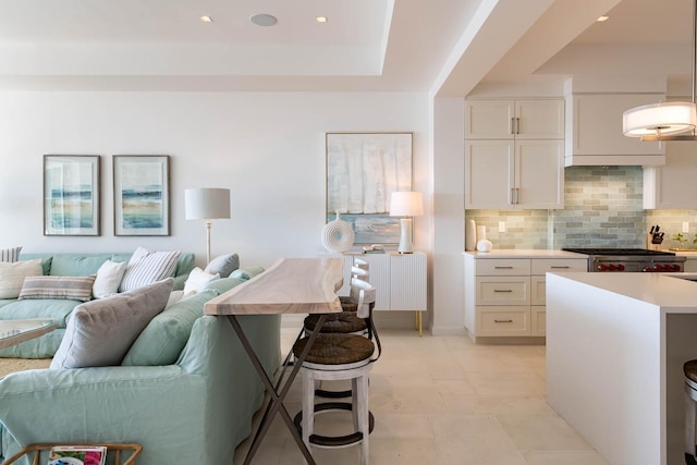 kitchen with hanging light fixtures, a tray ceiling, tasteful backsplash, and white cabinetry