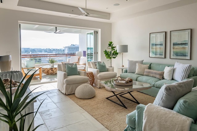 tiled living room featuring ceiling fan and a tray ceiling