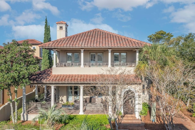 rear view of property with covered porch and a balcony