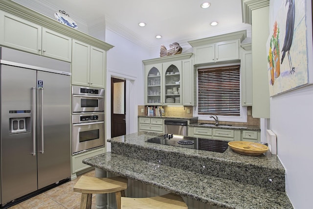 kitchen with stainless steel appliances, dark stone countertops, crown molding, a breakfast bar area, and decorative backsplash