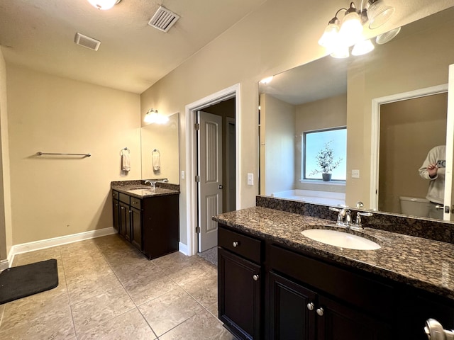 bathroom featuring vanity, a tub to relax in, tile patterned floors, and toilet