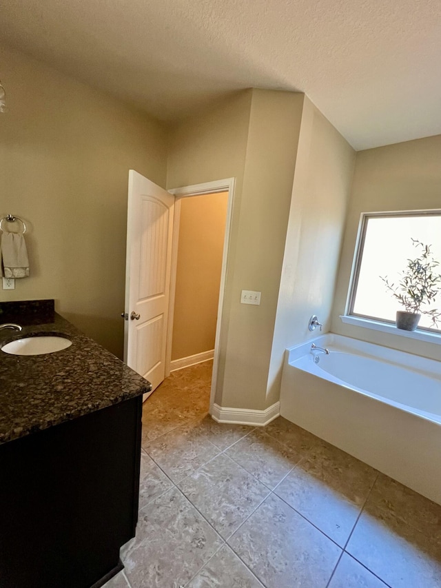 bathroom featuring vanity, tile patterned flooring, a bathtub, and a textured ceiling