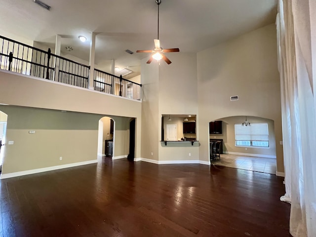 unfurnished living room with ceiling fan, dark hardwood / wood-style flooring, and a high ceiling