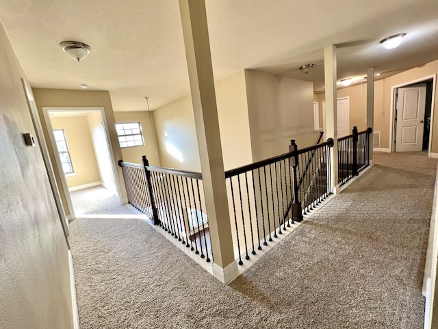 corridor with carpet floors and a textured ceiling