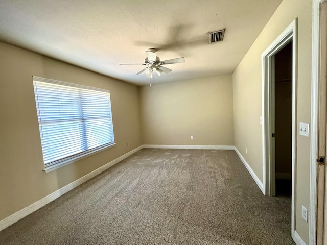 spare room featuring ceiling fan and dark carpet