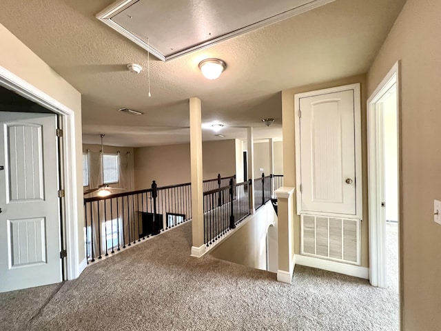 hall featuring carpet flooring and a textured ceiling