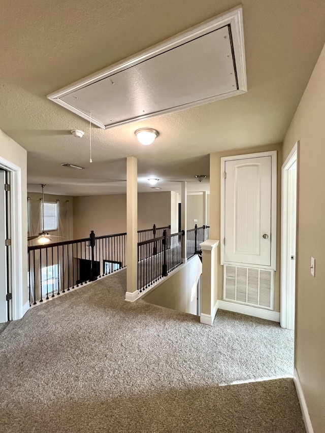 hallway featuring a textured ceiling and carpet flooring