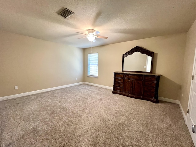 unfurnished bedroom with ceiling fan, light colored carpet, and a textured ceiling