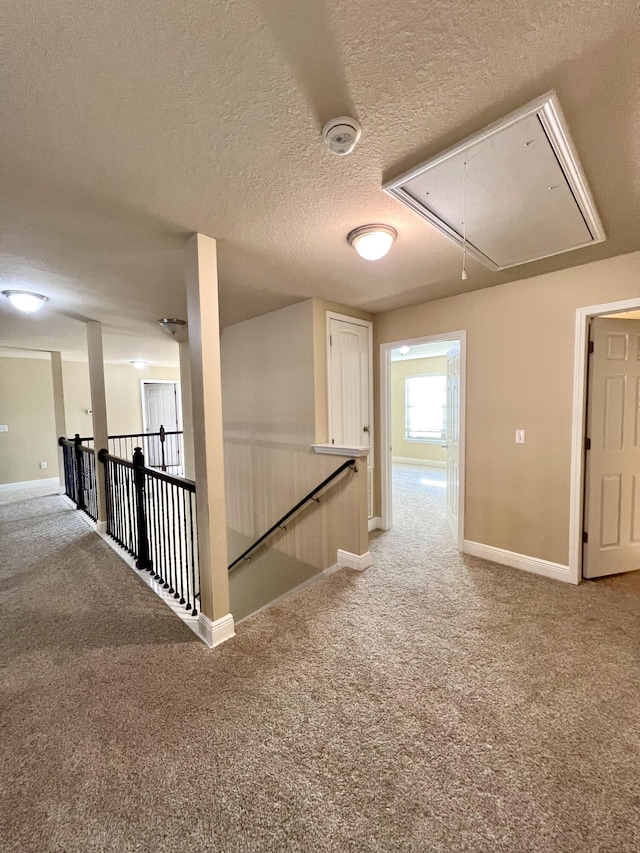 corridor with a textured ceiling and carpet flooring