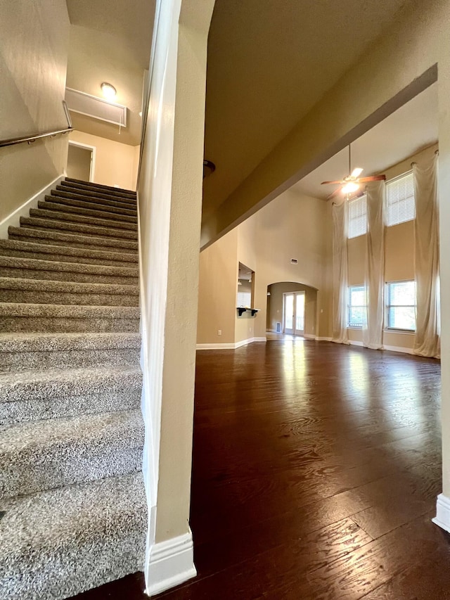 staircase featuring ceiling fan, hardwood / wood-style floors, and a towering ceiling