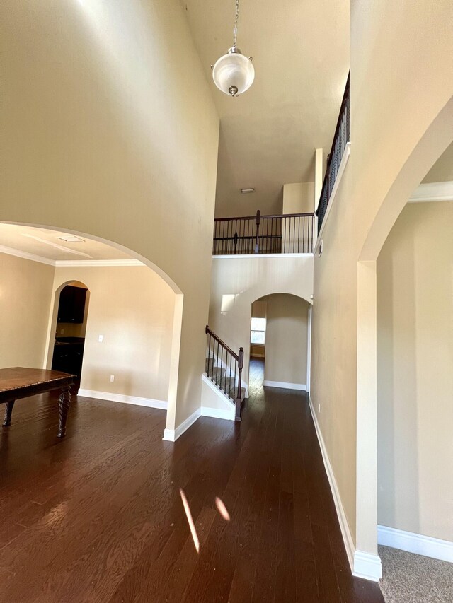 interior space featuring crown molding, a towering ceiling, and dark hardwood / wood-style flooring