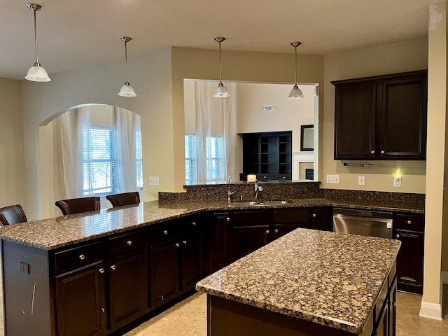 kitchen with dark brown cabinetry, dishwasher, a kitchen bar, and kitchen peninsula