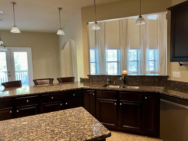 kitchen with pendant lighting, sink, a wealth of natural light, stainless steel dishwasher, and dark stone counters