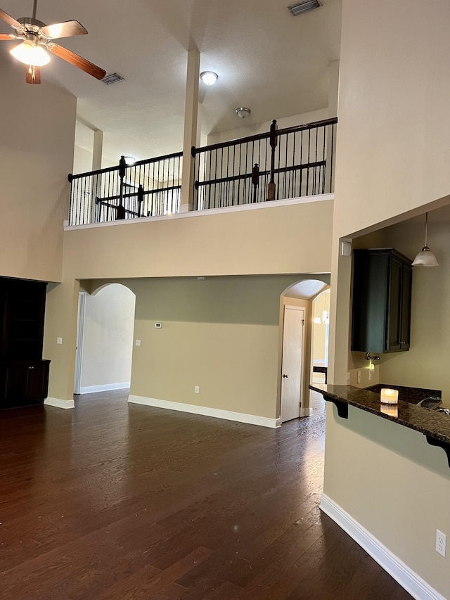 unfurnished living room featuring ceiling fan, a towering ceiling, and dark hardwood / wood-style flooring