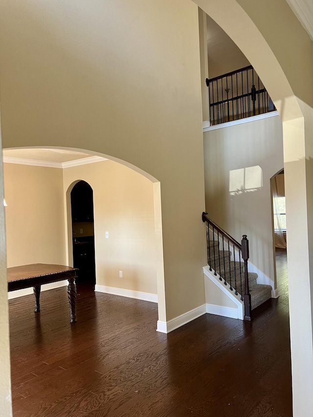 staircase with a high ceiling, crown molding, and wood-type flooring