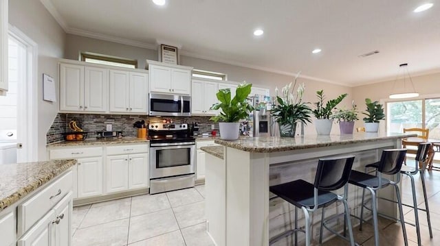 kitchen with appliances with stainless steel finishes, tasteful backsplash, pendant lighting, a center island, and white cabinetry