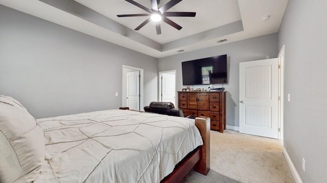 bedroom with light colored carpet, a raised ceiling, and ceiling fan