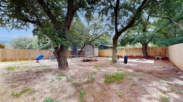 view of yard with a playground, a trampoline, and a fire pit